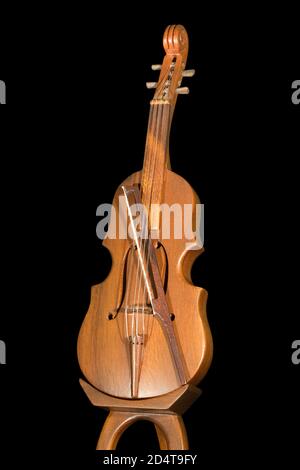 Modèle en bois d'un violon avec un arc, isolé sur fond noir Banque D'Images