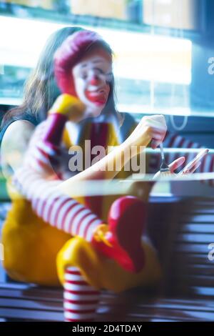 Bangkok, Thaïlande - 9 JUILLET 2019 : une statue de Ronald McDonald et une réflexion de femme asiatique sur le miroir du restaurant de restauration rapide McDonald's. Bangkok. Banque D'Images