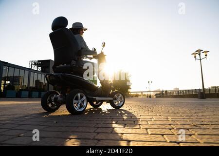 Femme touriste à bord d'un scooter électrique à quatre roues sur une rue de la ville. Banque D'Images