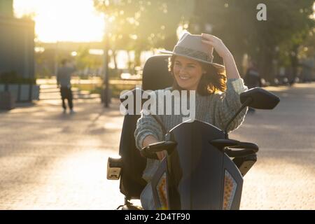 Femme touriste à bord d'un scooter électrique à quatre roues sur une rue de la ville. Banque D'Images