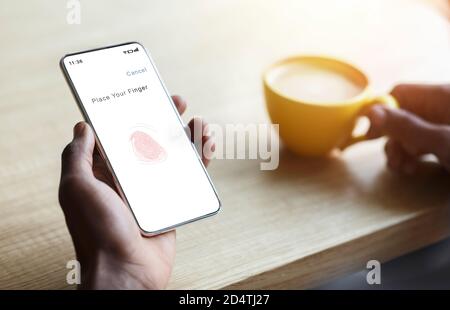 Personne tenant le téléphone avec le processus de numérisation avec empreinte digitale Banque D'Images