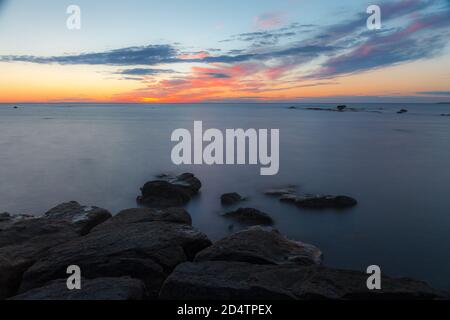 Coucher de soleil au crépuscule sur la côte rocheuse de la mer Baltique. Ciel presque clair et sangle orange le long de la horison. Estonie. Banque D'Images