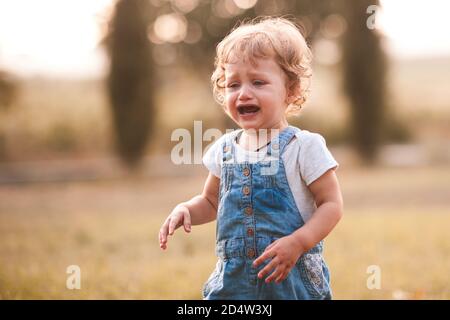 Pleurs fille 1-2 yea rold dehors. Enfant triste sur fond de nature. Enfance. Banque D'Images