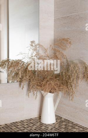 branches d'herbe de pampas naturelle séchée dans une carafe en métal sur le comptoir dans la salle de bains. Banque D'Images