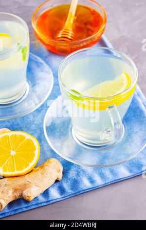 Thé au gingembre et citron sur une serviette bleue. Deux tasses de thé au gingembre, de miel et de divers ingrédients Banque D'Images