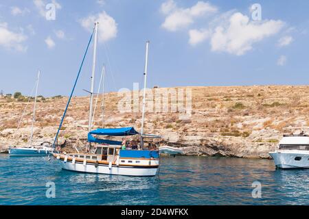 Mgarr ix-Xini, Malte - 27 août 2019 : vue sur la baie de Mgarr ix-Xini avec des personnes se détendant sur des yachts et des chauves-souris de plaisir lors d'une journée ensoleillée d'été Banque D'Images