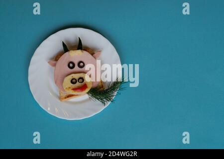 Idée drôle de petit déjeuner pour les enfants. Sandwich en forme de vache à bœuf à base de pain, saucisse, fromage. Vue de dessus de la nourriture de Noël du nouvel an avec espace pour les copies Banque D'Images