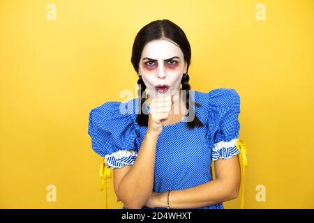 femme portant une poupée effrayante costume d'halloween sur fond jaune toux Banque D'Images