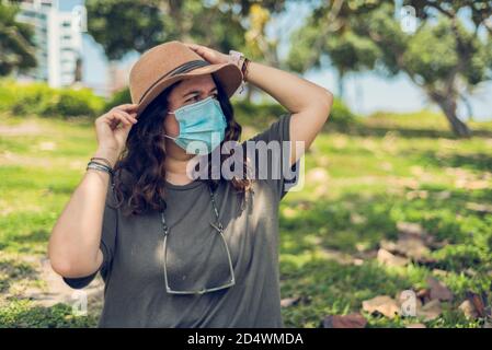 Portrait d'une femme dans un chapeau et masque médical appréciant la journée. Nouvelle normale. Copier l'espace Banque D'Images