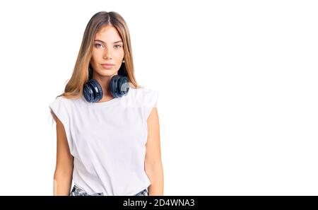 Belle femme caucasienne avec cheveux blonds écouter de la musique porter des écouteurs avec une expression sérieuse sur le visage. Simple et naturel regarder le CA Banque D'Images