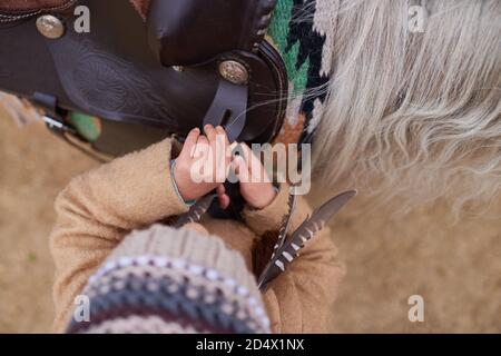 Petite fille fixing cheval Saddle Banque D'Images