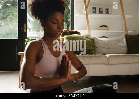 Une adolescente tient la position de prière pendant le flux de yoga assis salon moderne Banque D'Images