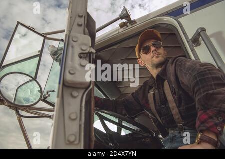 Chauffeur de camion caucasien professionnel dans ses 40 ans en cabine semi-camion appréciant la pause dans la zone de repos. Industrie du transport. Banque D'Images