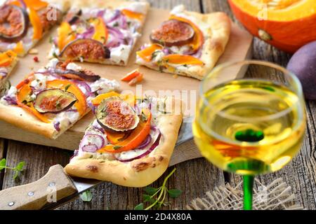 Tarte Flambee d'Alsace avec fromage à la crème de chèvre, oignons, tranches de citrouilles et figues, servi avec du vin alsacien local Banque D'Images