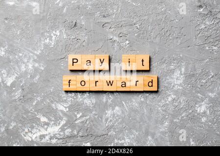 Mot Pay IT Forward écrit sur le bloc de bois. Payez-le Forward texte sur la table de ciment pour votre conception, concept. Banque D'Images