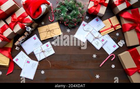 Table en bois décorée de joyeux Noël avec enveloppes et boîtes à cadeaux, vue du dessus. Banque D'Images