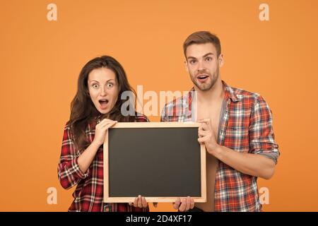 Couple avec tableau noir pour la publicité. Surpris couple jaune fond. Homme et femme publicité produits. Informations sur les réductions. Vente finale. C'est une grande surprise. Vraiment bonne nouvelle. Banque D'Images