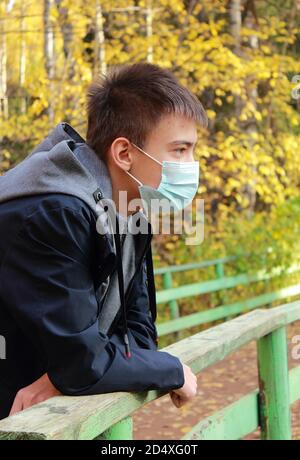 Portrait d'un garçon adolescent dans un masque de protection dans un parc d'automne Banque D'Images