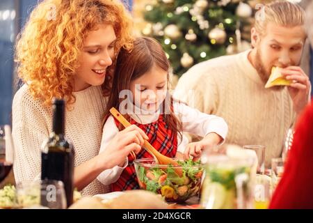 Famille assise derrière la table avec une salade fraîche Banque D'Images