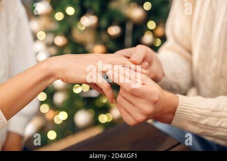 Main du Mans mettant l'anneau d'engagement sur le doigt des femmes à Noël Banque D'Images