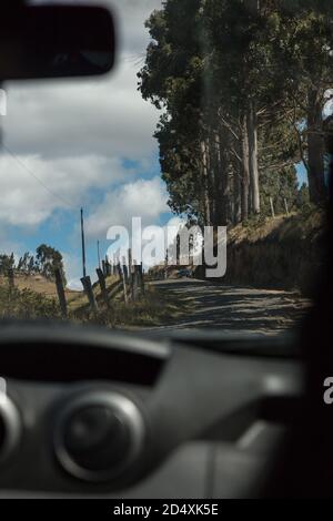 gros plan de l'intérieur d'une voiture, montrant le tableau de bord de la voiture, le pare-brise, dans le paysage d'arrière-plan d'une route de terre avec des arbres Banque D'Images