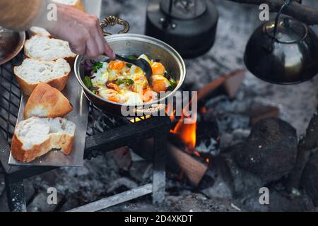 Vue détaillée de la cuisson au feu de camp, les pains sont dans une rangée, un pot à thé et une poêle à oeufs est sur le feu avec l'espace de copie Banque D'Images