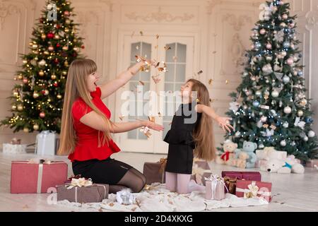 Petite fille avec maa jette confetti et ouvre des cadeaux. Magie de Noël. Des moments joyeux d'une enfance heureuse. Banque D'Images