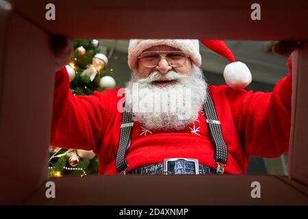 Vue rapprochée du cadeau d'emballage du Père Noël en regardant à l'intérieur de la boîte-cadeau. Banque D'Images