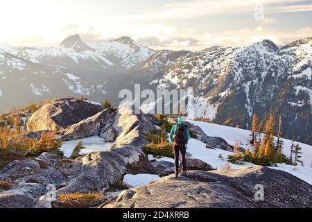 Une jeune femme qui se promenait dans les montagnes au coucher du soleil a avec vue sur les sommets enneigés, Needle Peak, Coquihalla, Colombie-Britannique, Canada Banque D'Images