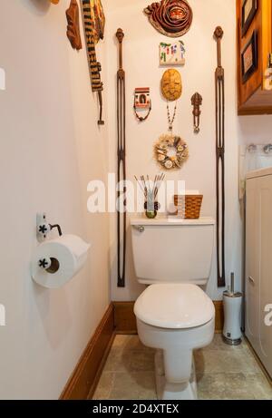 Salle de bains avec toilettes standard et murs décorés de diverses sculptures en bois à l'intérieur d'une ancienne maison de style Canadiana datant de 1840. Banque D'Images