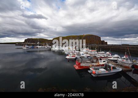 Port de Stykkishólmur avec falaise de Sugandisey et phare derrière. Snaefellsnes péninsulaire, Islande. Les bateaux sont attachés au quai lors d'une journée de débordement. Banque D'Images