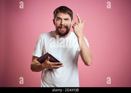 L'homme annonce une tablette sur fond rose codes espace vue rognée des émotions t-shirt blanc modèle nouvelles technologies Banque D'Images