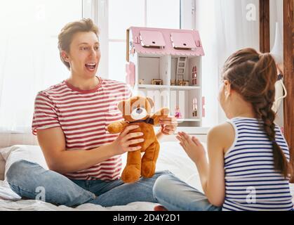 Un père heureux et une fille jouent avec des jouets à la maison. Une famille charmante et drôle s'amuse dans la chambre des enfants. Banque D'Images