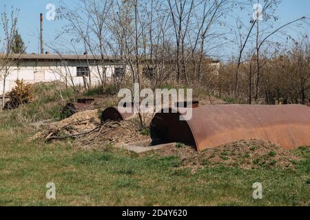 De vieux barils de rouille abandonnés sont à moitié enterrés dans le sol. Banque D'Images