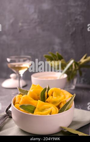 Tortellini à la sauge, à la ricotta et aux épinards. Pâtes italiennes et vin blanc. Cuisine traditionnelle de Bologne, région de l'Émilie-Romagne. Photo de haute qualité. Copier l'espace Banque D'Images