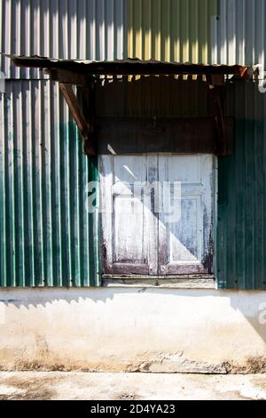 Vieux mur de zinc et de béton de la maison ancienne avec ombre de vieux auvent de fenêtre en bois. Banque D'Images