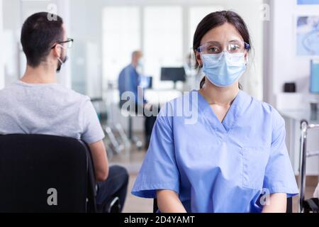 Assistant médical avec visière et masque facial contre le coronavirus pendant une pandémie mondiale. Médecin consultant l'homme senior dans la salle d'examen. Médecin, épidémie, soins, chirurgie, couloir. Banque D'Images