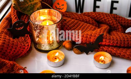 Bougies avec chandail et potiron fantôme, feuilles séchées sur le rebord de la fenêtre. Décoration de la maison d'Halloween. Fenêtre de pluie. Banque D'Images