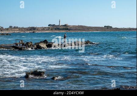 Un homme pêchant depuis les rochers près de l'hôtel de plage Kefalos, Kato Paphos, Chypre. Banque D'Images