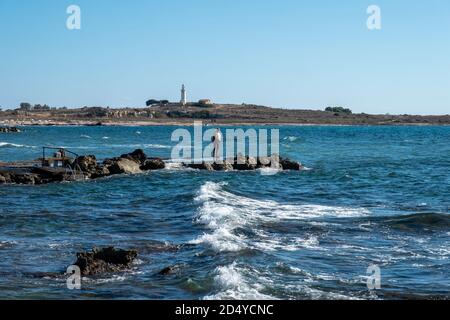 Un homme pêchant depuis les rochers près de l'hôtel de plage Kefalos, Kato Paphos, Chypre. Banque D'Images