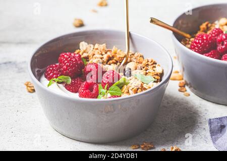 Muesli avec framboises et yaourt dans un bol gris. Concept alimentaire sain. Banque D'Images