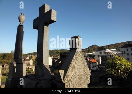 Pierres à tête dans le New Calton Burial Ground, Édimbourg, Écosse, avec le Parlement écossais, et Arthur's Seat. Banque D'Images