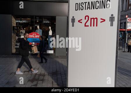 Les Londoniens passent un signe de distanciation sociale qui exhorte le public à se tenir à 2 mètres de distance sur Oxford Street pendant la deuxième vague (automne) de la pandémie du coronavirus, le 8 octobre 2020, à Londres, en Angleterre. Banque D'Images