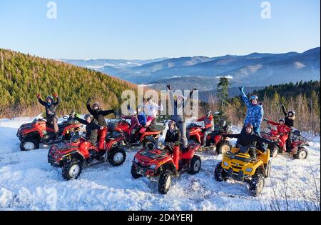 Yaremche, Ukraine - 02 février 2020: Groupe de personnes gaies assis sur des VTT, s'amuser sur une belle journée d'hiver dans des montagnes enneigées, crête de montagne à couper le souffle sur le fond. Banque D'Images