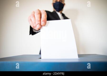 femme portant un masque mettant le vote au scrutin Banque D'Images