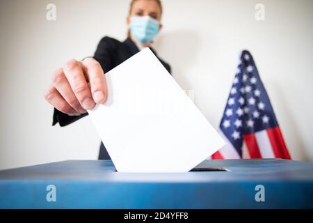 femme portant un masque mettant le vote au scrutin Banque D'Images