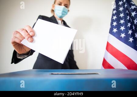 femme portant un masque mettant le vote au scrutin Banque D'Images