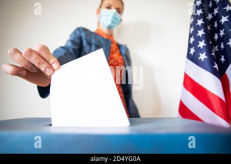 femme portant un masque mettant le vote au scrutin Banque D'Images