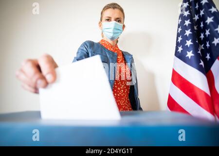 femme portant un masque mettant le vote au scrutin Banque D'Images