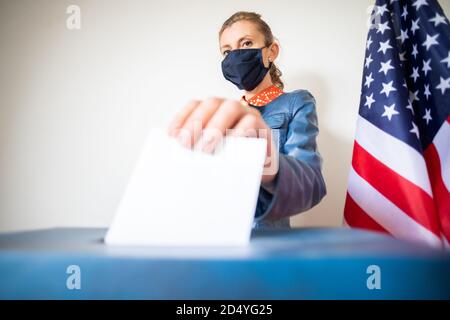 femme portant un masque mettant le vote au scrutin Banque D'Images